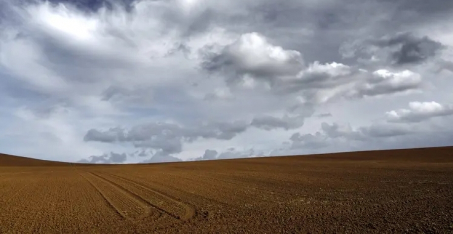 The brown sandy land under the dark cloudy grey sky (Freepik)